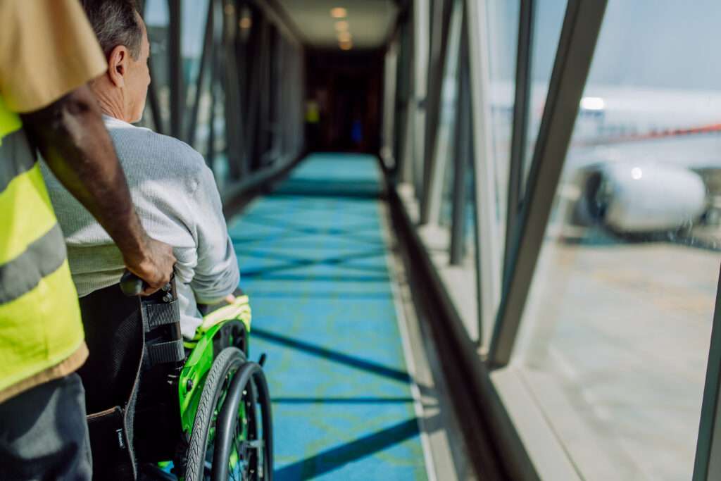 rear view of airport worker pushing man on wheelch 2023 11 27 05 08 01 utc